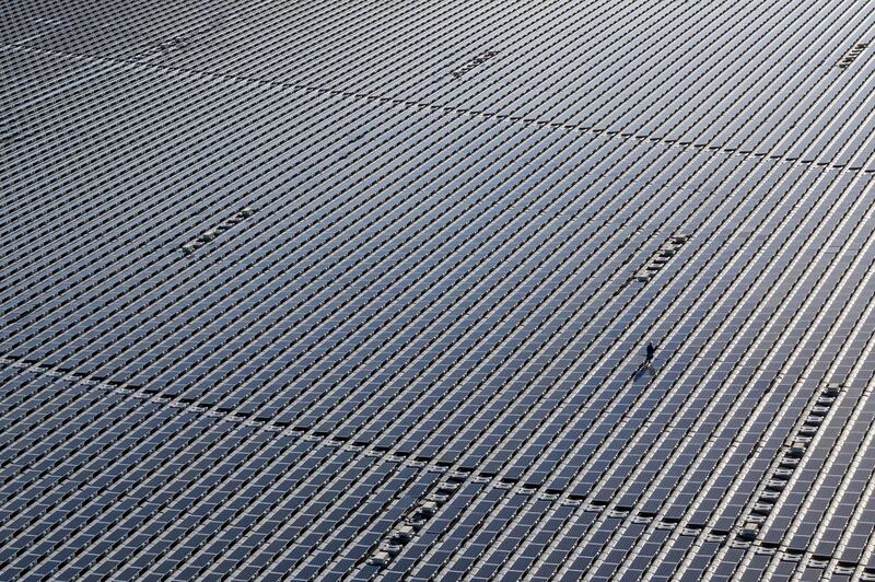 An engineer walks between panels on the Yamakura Dam floating solar plant in Ichihara, Japan. Getty Images