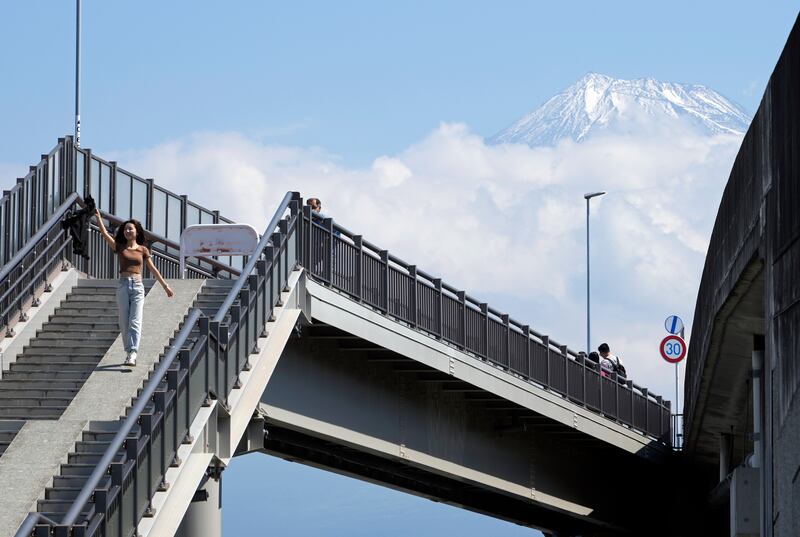 A tourist walks down the stairs leading to the Fujisan Yumeno Ohashi, or Mount Fuji Great Dream Bridge, as Mount Fuji looms in the background in Fuji City, Shizuoka prefecture, central Japan, on June 8. EPA