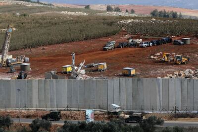 A picture taken on December 5, 2018 in the southern Lebanese village of Kfar Kila near the border with Israel shows Israeli machinery (top) operating next to the concrete border wall. Israel had announced on December 4 that it had discovered Hezbollah tunnels infiltrating its territory from Lebanon and launched an operation to destroy them. / AFP / Mahmoud ZAYYAT
