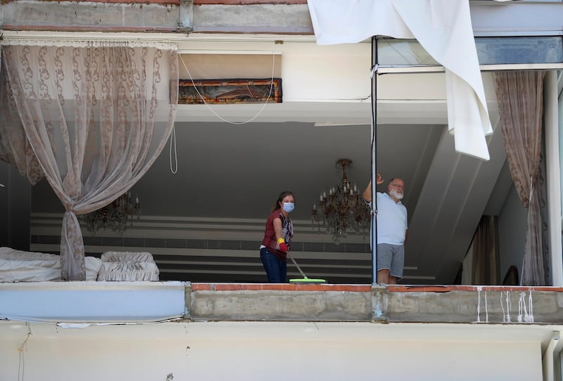 A woman cleans debris from her damaged apartment a day after an explosion hit the seaport of Beirut. AP Photo