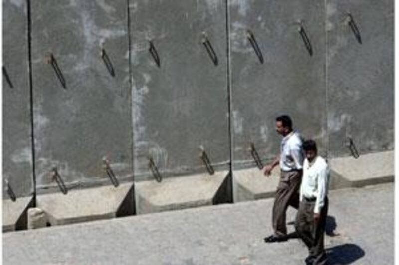 Two men walking past a blast wall in central Baghdad, Iraq.  Maj Gen Qassim al Moussawi, the spokesman for the city's operations command center, said the walls will be taken off major thoroughfares and secondary roads in the capital.