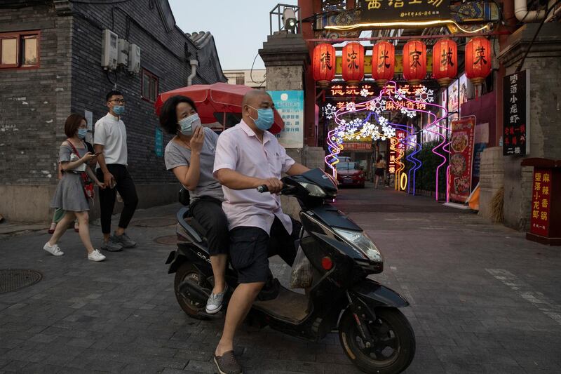 Residents pass by lanterns and neon lights promoting a restaurant in Beijing. AP Photo