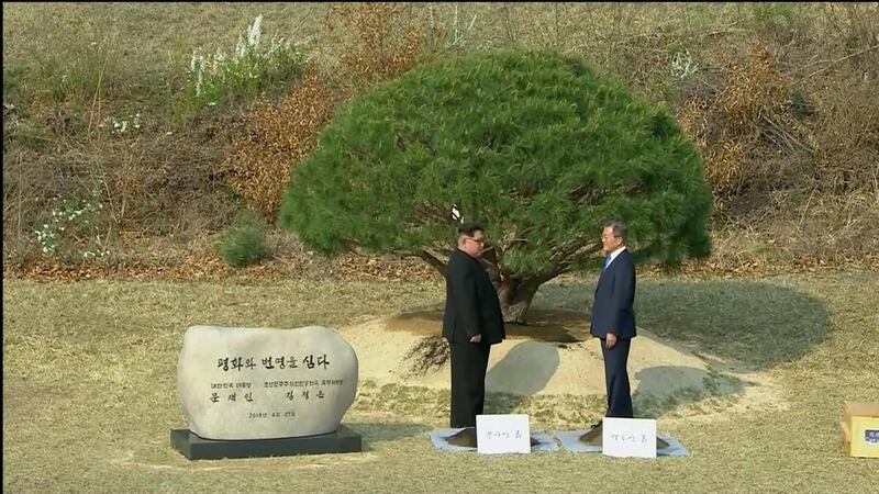 The leaders pose for a photograph after tending to a pine tree in the truce village. Host Broadcaster via Reuters