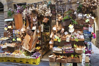 Florence, Italy - Sep 22, 2015: Urban street scene of an elaborate, crowded, charming front entrance display at a retail grocery store, featuring fruits, vegetables, and housewares, Florence, Italy.