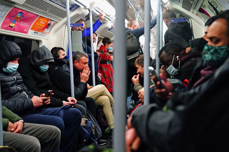 Commuters, some wearing face masks, sit in a London Underground train during rush hour. PA
