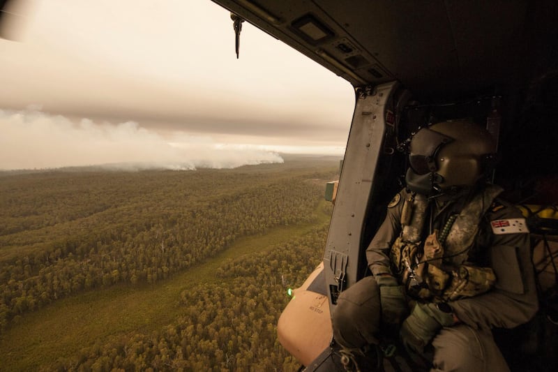 A Royal Australian Navy MRH-90 helicopter crew member looks out over fires burning near Cann River. The wildfires have so far scorched an area twice the size of the US state of Maryland. AP