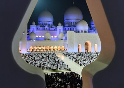 This picture taken early on June 1, 2019 through the crenellations of the Sheikh Zayed Grand Mosque in the UAE capital Abu Dhabi shows Muslim worshippers praying in the mosque's courtyard on the occasion of Lailat al-Qadr, which marks the night in the fasting month of Ramadan during which the Koran was first revealed to Prophet Mohammed in the seventh century.  / AFP / KARIM SAHIB
