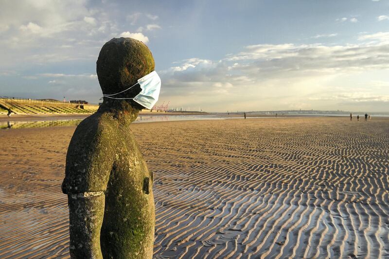 LIVERPOOL, ENGLAND - FEBRUARY 10:  One of the 100 life-size body cast statues of 'Another Place' at Crosby beach, created by the artist Sir Antony Gormley wears a Covid-19, coronavirus  face mask during the pandemic lockdown Crosby on February 10, 2021 in Liverpool, England.  (Photo by Christopher Furlong/Getty Images)