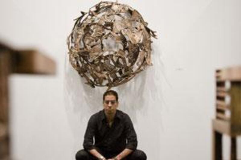 Amin Gulgee kneels beneath one of his pieces at the opening of his new show at Artspace in Dubai.