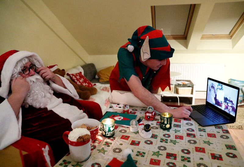 An assistant helps Pal Pillmayer, dressed as Santa Claus, as he prepares to interact with children by video chat in Budapest, Hungary. Reuters