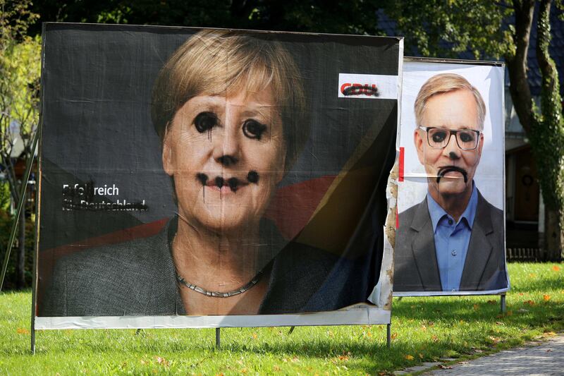Defaced election campaign posters of Angela Merkel's Christian Democratic Union CDU and of Die Linke party are pictured in Altenberg, Germany, September 27, 2017. Picture taken September 27, 2017.       REUTERS/Matthias Schumann