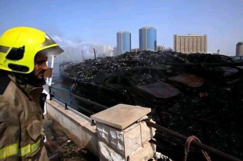 Dubai Civil Defence sprays water to the burnt cargo dhow at the Dubai Creek in Dubai.