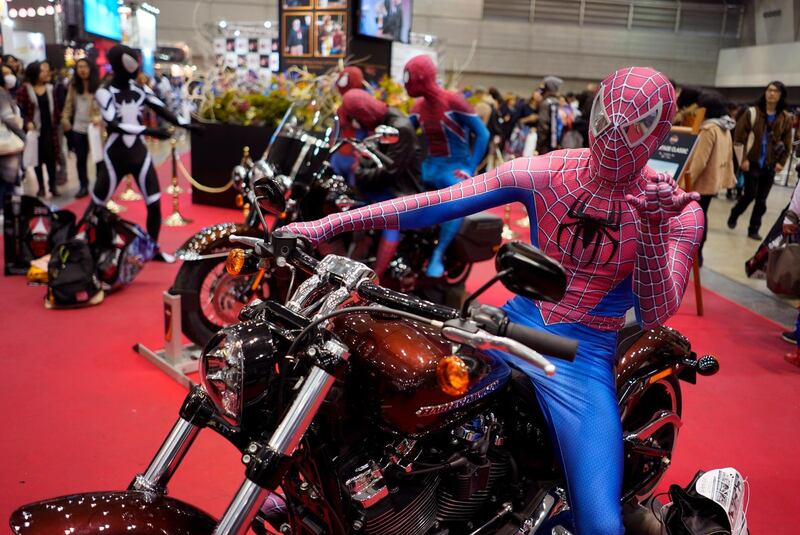 An attendee wearing a Spider-Man costume sits astride a motorbike. EPA