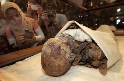 (FILES) In this file photo taken on June 27, 2007, people take pictures of the mummified remains of Queen Hatshepsut, ancient Egypt's most famous female pharaoh, displayed in a glass case after being unveiled at the Cairo Museum. The mummies of 18 ancient Egyptian kings and four queens will be paraded through the streets of Cairo on April 3 evening, in a carnival procession dubbed the Pharaohs' Golden Parade, as they are moved from a long residency at the Egyptian Museum to be put on display at southern Cairo's National Museum of Egyptian Civilisation. / AFP / Cris BOURONCLE
