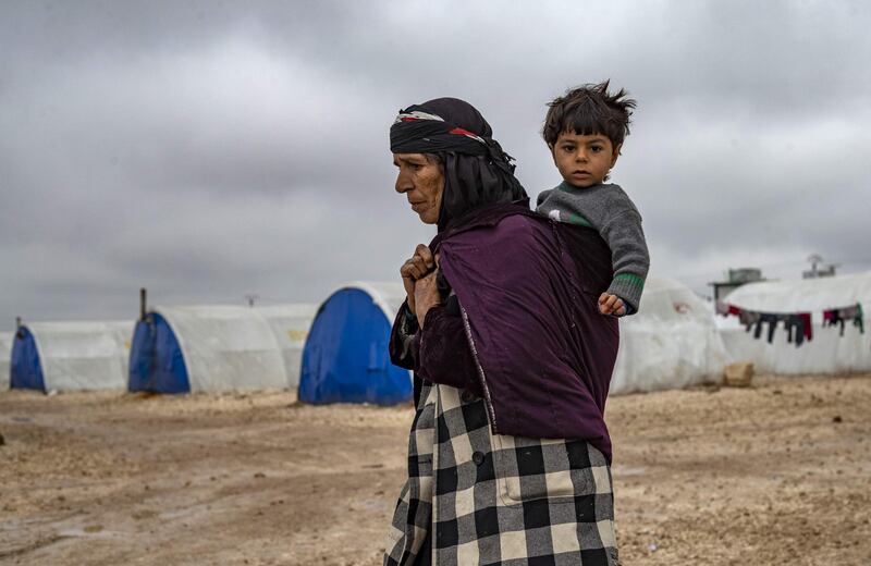 An elderly displaced Syrian woman carries a child in the Washukanni Camp for the internally displaced people near the predominantly Kurdish city of Hasakeh in northeastern Syria.  AFP