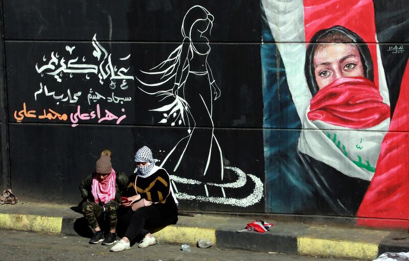 Female protesters sit next to a wall painted with a graffiti during ongoing anti-government protests at the Al Tahrir square in central Baghdad, Iraq.  EPA
