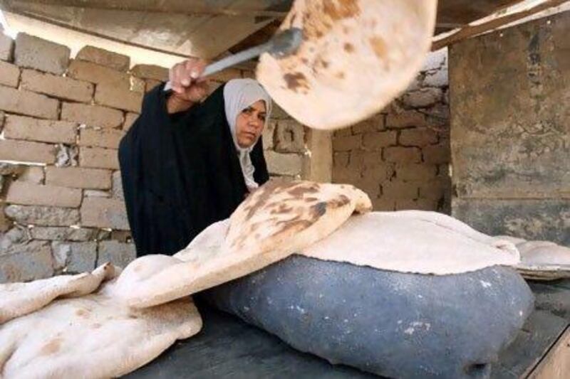 An Iraqi woman, making bread in a traditional bakery, has seen the price of flour rise three-fold in the last two months. Ali al Saadi / AFP