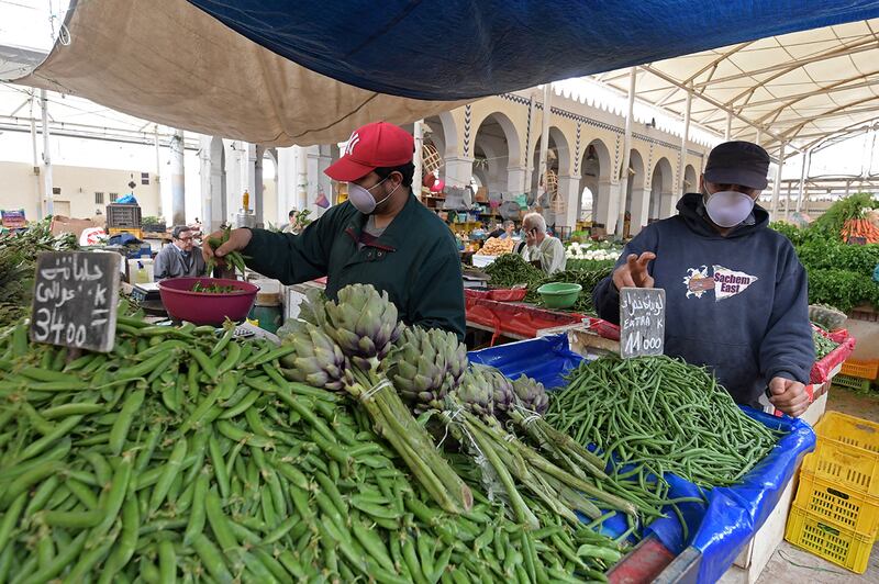 A Tunisian vendor, wearing a protective mask, weighs vegetables at a stall in a central market in the capital Tunis on April 24, 2020, during the first day of the Muslim holy month of Ramadan, after authorities partially eased the lockdown measures. (Photo by FETHI BELAID / AFP)
