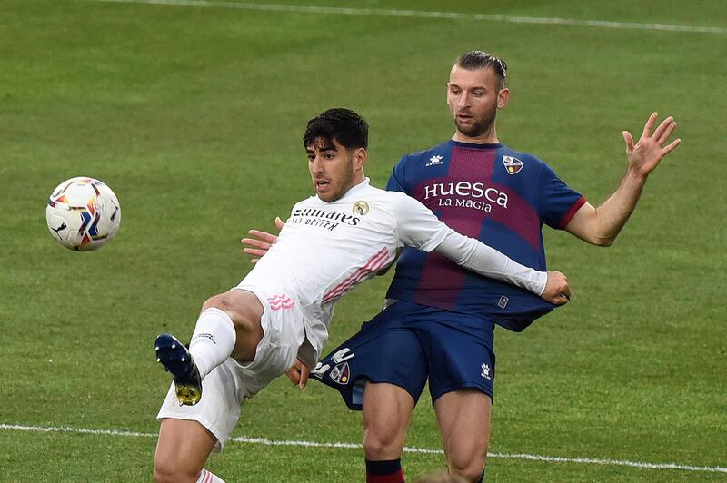 Real Madrid's Marco Asensio holds off  Gaston Silva of Huesca. EPA