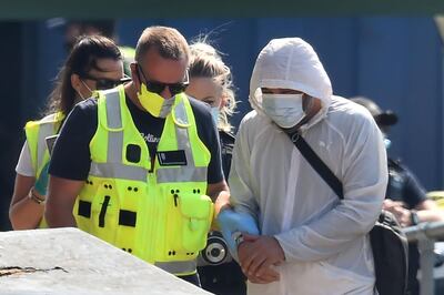 A UK Border Force officer processes a migrant, believed to have been picked up from a boat in the Channel, in the port of Dover, on the south-east coast of England on August 9, 2020.  The British government on Sunday appointed a former marine to lead efforts to tackle illegal migration in the Channel ahead of talks with France on how to stop the dangerous crossings. / AFP / Glyn KIRK                  
