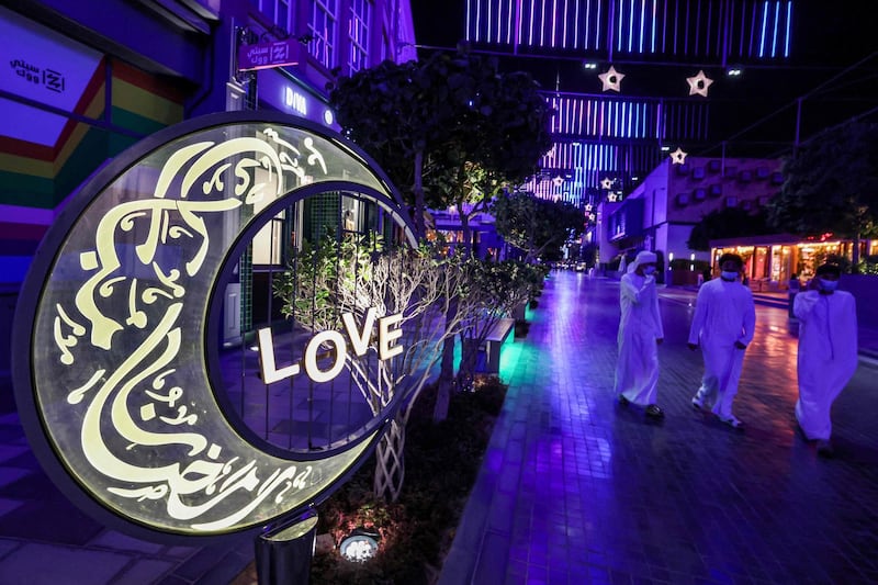 Emirati youths walk past a large lit decoration in the shape of a crescent moon bearing calligraphic text in Arabic reading "Ramadan Mubarak", at the City Walk district of Dubai at the start of the first night of the Muslim holy fasting month of Ramadan. AFP