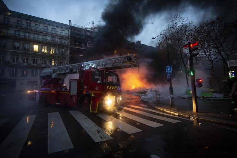 Firefighters work to put out cars set on fire on a road nearby Arc de Triomphe in Paris, France. Getty Images