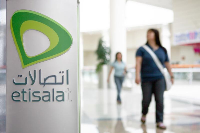 People walk by an Etisalat sign inside a mall in Abu Dhabi. Galen Clarke / The National