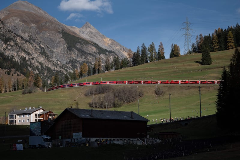 The 1,910-metre-long train with 100 cars passes through the Swiss mountains.