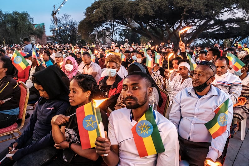 People hold candles and Ethiopian flags at a memorial service for the victims of the Tigray conflict in Addis Ababa.