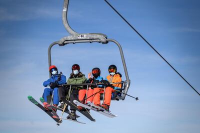 Skiers, some wearing protective face masks against the spread of the Covid-10 (novel coronavirus), ride a ski lift before hitting the slopes during the first snows of the season above the ski resort of Verbier in the Swiss Alps on November 15, 2020. - The coronavirus crisis shuttered Switzerland's ski resorts in the spring, but they are banking on tighter precautions and the Swiss love of the mountains to save them as the winter season begins. (Photo by Fabrice COFFRINI / AFP)