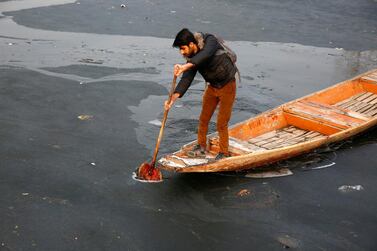 epa08094596 A Kashmiri boy tries to break the ice as he rows his boat on Dal Lake on a cold morning in Srinagar, Kashmir, 30 December 2019. Kashmir is currently going through the 'Chillai-Kalan', the 40-day harshest period of winter, when temperatures drop considerably. EPA/FAROOQ KHAN