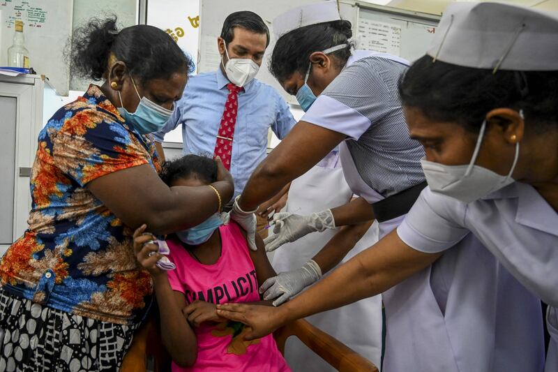 A health worker inoculates a child with a dose of the Pfizer-BioNTech vaccine against the Covid-19 coronavirus at a children's hospital in Colombo.  AFP