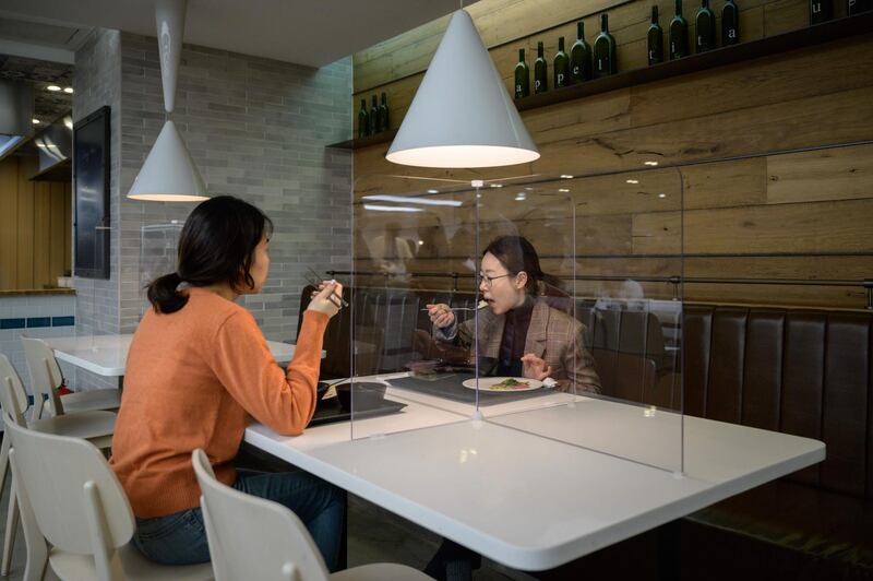 At a cafeteria in Seoul on April 9, employees eat behind protective screens as part of preventative measures at the offices of Hyundai Card credit card company that has implemented reduced working hours and staggered lunch breaks, while South Korea has seen a continued decline in new virus cases. Ed Jones/ AFP