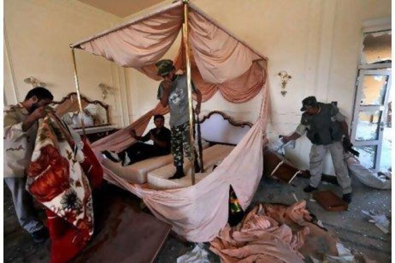 National Transitional Council fighters search a room at Muammar Qaddafi's Sirte palace yesterday. The council says it is near to claiming full control of the fugitive leader's hometown after seizing a convention centre that had served as a key base for his forces. Aris Messinis / AFP