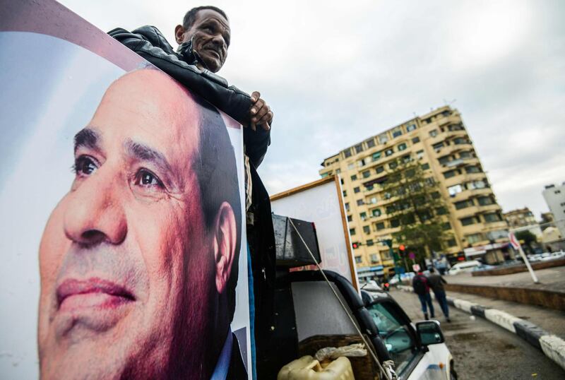 A supporter of Egyptian President Abdel Fattah al-Sisi stands in the back of a pickup truck bearing his portrait and loudspeakers, in the capital Cairo's Tahrir square on January 25, 2018, as the country marks the seventh anniversary of the 2011 uprising that ended the 30-year reign of former President Hosni Mubarak. / AFP PHOTO / MOHAMED EL-SHAHED