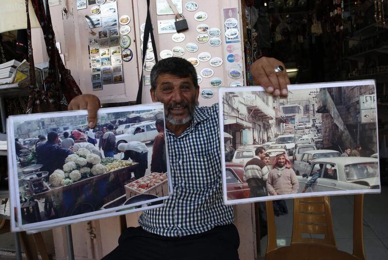 A 59-year-old Palestinian man who runs a stall in the old town of Hebron holding photos showing the market full of Palestinians in the early years following the 1967 Six-Day war. Hazem Bader / AFP 