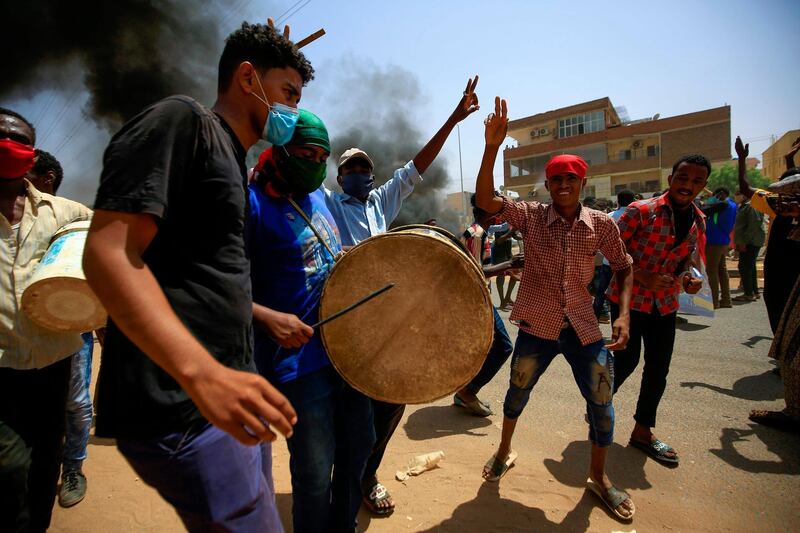Sudanese demonstrators bang the drum and dance during a protest on Sixty street in the east of the capital Khartoum, on June 30, 2020. Tens of thousands of Sudanese took to the streets in several cities and the capital calling for reforms and demanding justice for those killed in anti-government demonstrations that ousted president Omar al-Bashir last year. The protests went ahead with security forces deployed in force and despite a tight curfew since April designed to curb the spread of the novel coronavirus. / AFP / ASHRAF SHAZLY
