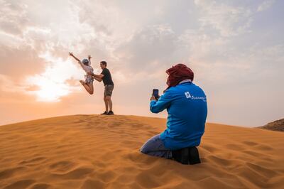 An OceanAir Travels guide takes pictures of tourists enjoying the red sand dunes in Dubai. Photo: OceanAir Travels