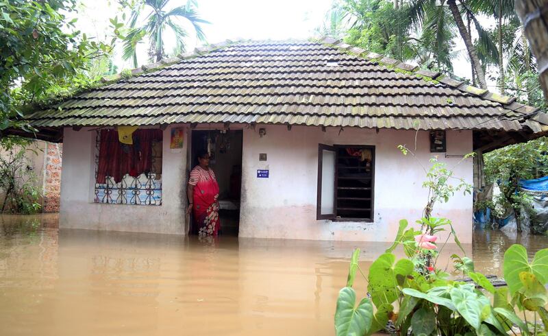 A woman stands at the door of her flooded home.  EPA