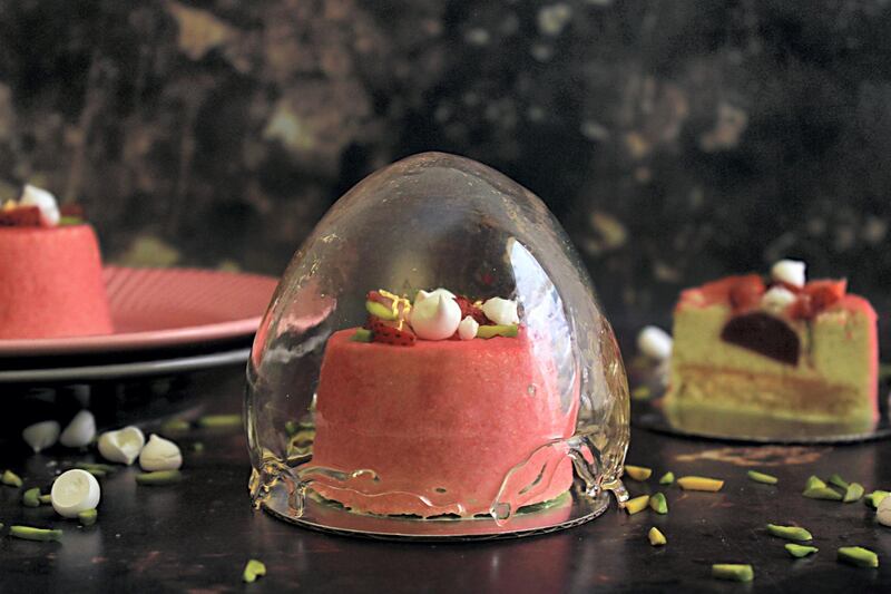 Khan's sugar globe dessert, a pistachio mousse and vanilla cake with a strawberry jam centre, velvet sprayed and topped with strawberries, meringue kisses, and pistachios