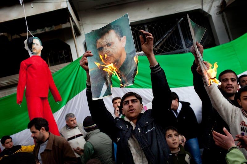 People burn portraits of Assad during a demonstration on the outskirts of Idlib.