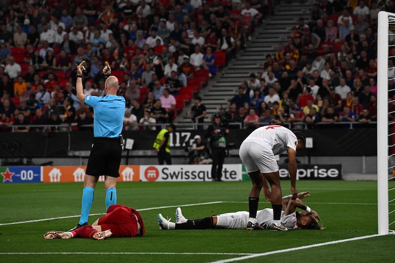 Referee Anthony Taylor calls for medics after a clash of heads between Sevilla's Nemanja Gudelj and Roma's Roger Ibanez. AFP