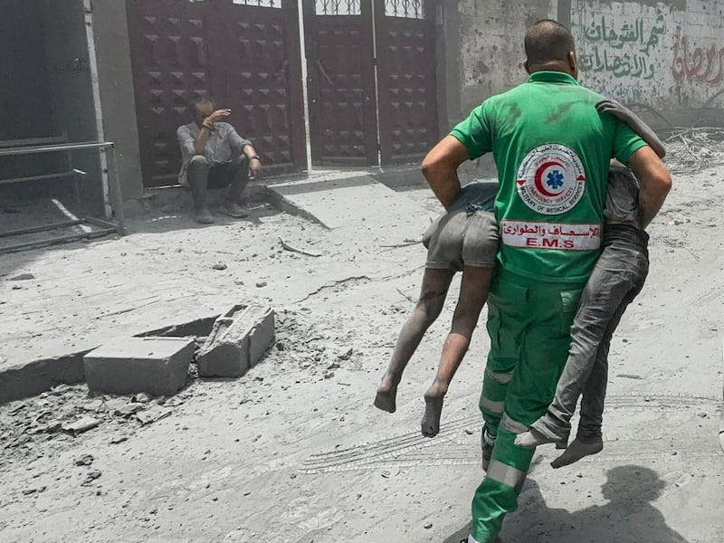 A Palestinian rescue worker carries wounded civilians at the site of Israeli strikes on houses in Gaza City on Saturday. Reuters