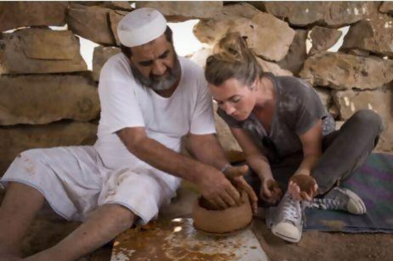 Ruth Impey, a professional potter based in Abu Dhabi learns to make a traditional pot from Ahmed Rashed Mohammed Al Haymar, 60, in his father's old home in Wadi Haqil. Razan Alzayani / The National