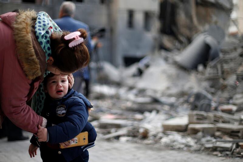 A woman comforts her son outside their destroyed house in Gaza City. Reuters
