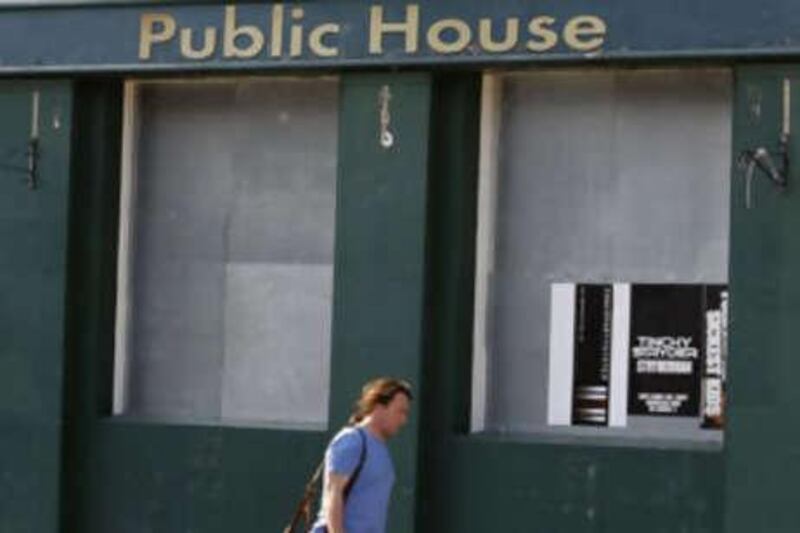 A man walks past a boarded-up pub for sale in west London.