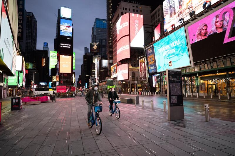 People ride bicycle in New York's Times Square, Wednesday night, during the coronavirus pandemic. President Donald Trump said Wednesday the federal government will not be extending its coronavirus social distancing guidelines once they expire Thursday. AP