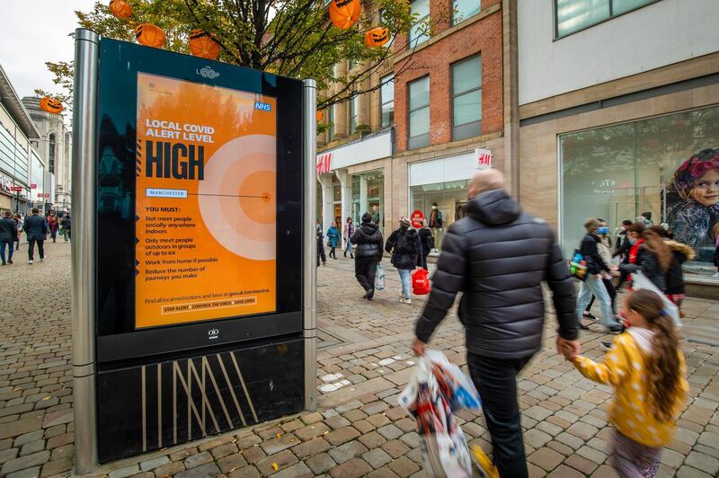 Pedestrians pass an advertising sign displaying that the Local Covid Alert Level is High in Manchester. Bloomberg