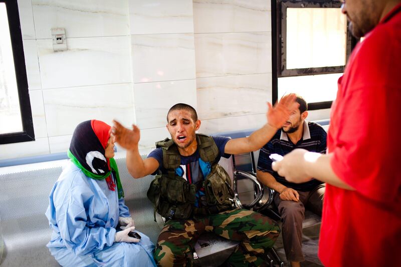 TRIPOLI, LIBYA - AUGUST 25: A Libyan Rebel soldier reacts after a fellow fighter (unseen) was brought in with a wound, sustained in battle with pro-Gaddafi loyalists, to the Tripoli Central Hospital on August 25, 2011 in Tripoli, Libya. Heavy fighting continues in the Libyan capital between Gaddafi's forces and the surging rebel presence. The Rebels, who have issued a $1.7m reward for Gaddafi's capture "dead or alive", are attempting to reach Colonel Gaddafi's hometown of Sirte but have met loyalist resistance. (Photo by Daniel Berehulak/Getty Images) *** Local Caption ***  122129691.jpg