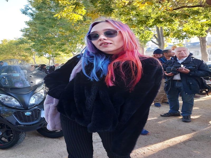 A young woman with pink and blue hair outside Chanel.